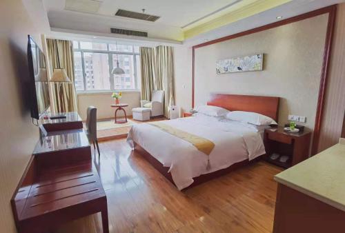 a hotel room with a large bed and a desk at Vienna Hotel Nantong Tongzhou Bus Station in Tongzhou