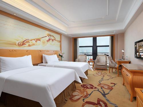 a hotel room with three beds and a television at Vienna International Hotel Jiujiang Shili Street in Jiujiang