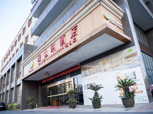 Vienna Hotel Jiangyin Qishan Road في جيانغ: يوجد متجر أمام مبنى به نباتات الفخار في الأمام