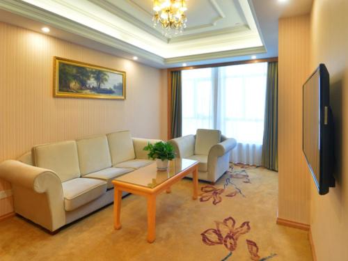 uma sala de estar com um sofá e uma mesa em Vienna International Hotel Meizhou Dingzi Bridge em Meizhou