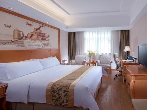 Cette chambre comprend un grand lit et un bureau. dans l'établissement Vienna International Hotel Guangzhou Railway Station, à Canton