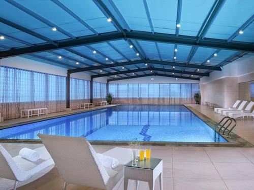 a large swimming pool in a hotel with chairs and a table at Venus Royal Hotel Guilin Airport in Guilin