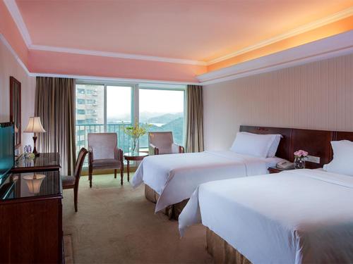 a hotel room with two beds and a window at Vienna Hotel Shenzhen Aiguo Road in Shenzhen