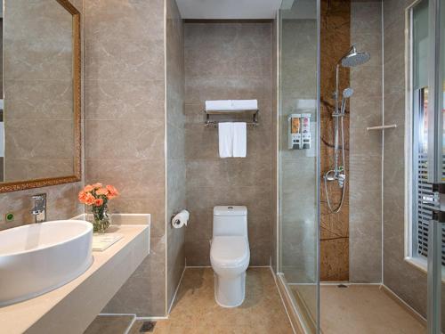 a bathroom with a toilet and a sink and a shower at Vienna International Hotel Shenzhen South Huanguan Road in Bao'an