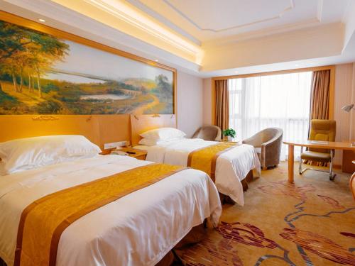 a hotel room with two beds and a painting on the wall at Vienna International Hotel Shanghai Pudong New District Dishui Lake Univeristy City in Nianbalian
