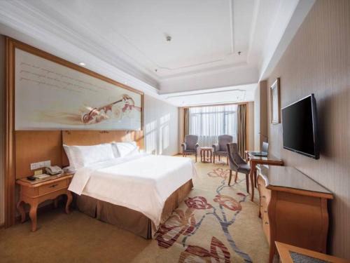 a hotel room with a bed and a flat screen tv at Vienna Hotel Hunan Hengyang Railway Station in Hengyang