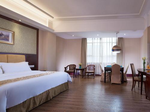 a hotel room with a bed and a dining room at Vienna Hotel Dongguan Changping Avenue in Dongguan