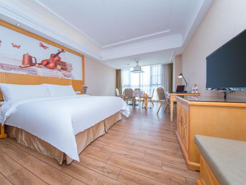 a hotel room with a large bed and a flat screen tv at Vienna Hotel Hubei Xiangyang Tanxi Road in Xiangyang