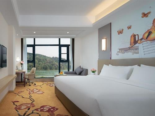 um quarto com uma grande cama branca e uma grande janela em Vienna Hotels(JingHong BinJiang JunJuan) em Jinghong