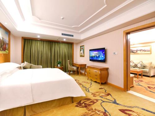 Vienna International Hotel Changsha Ziwei Road في تشانغشا: غرفة نوم مع سرير أبيض كبير ومكتب