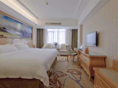 Habitación de hotel con cama grande y TV en Vienna Hotel Jiujiang Railway Station, en Jiujiang