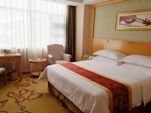 a hotel room with a large bed and a chair at Vienna Hotel Sanya Yalong Bay Qianguqing in Sanya