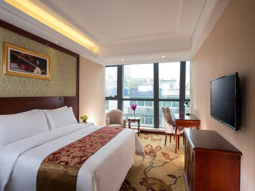a hotel room with a bed and a flat screen tv at Vienna Hotel Shunde Longjia Exhibition Center in Shunde
