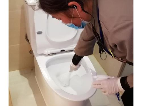 a person is cleaning a toilet in a bathroom at Vienna International Hotel (Jiaxing Nanhu Hotel) in Jiaxing