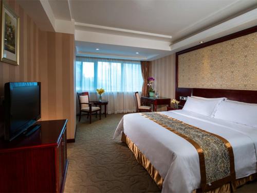ein Hotelzimmer mit einem großen Bett und einem TV in der Unterkunft Vienna Hotel Shenzhen Fenghuang Road in Shenzhen