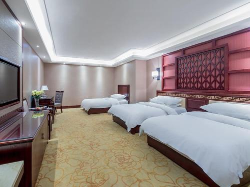 um quarto de hotel com 4 camas e uma televisão de ecrã plano em Vienna Hotel Kunming North Caiyun Road Asia em Kunming