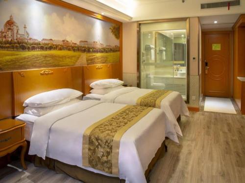 a hotel room with three beds and a painting on the wall at Vienna Hotel Shanghai Yangpu Wujiaochang in Shanghai
