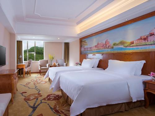 深圳的住宿－維也納國際酒店深圳草埔金稻田店，一间卧室设有两张床,墙上挂着一幅大画