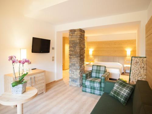 a living room with a room with a bed and a couch at Hotel Europeo Alpine Charme & Wellness in Pinzolo