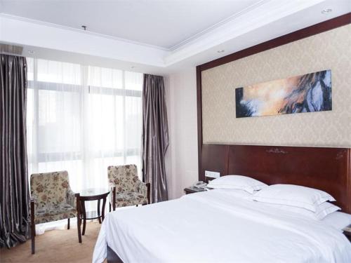 Vienna Hotel Jiangyin Qishan Road في جيانغ: غرفة فندقية بسرير وطاولة وكراسي