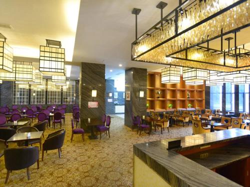 a restaurant with purple chairs and tables and a bar at Vienna International Hotel Yangzhou Libao Square in Yangzhou