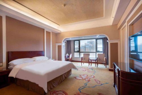 宝安にあるVienna Hotel Shenzhen Songgang Liye Roadの大きなベッドと大きな窓のある寝室