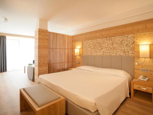 a bedroom with a large white bed and wooden walls at Hotel Europeo Alpine Charme & Wellness in Pinzolo