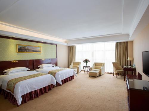 ein Hotelzimmer mit 2 Betten und einem Flachbild-TV in der Unterkunft Vienna Hotel Heyuan High-Tech Yi Road in Heyuan