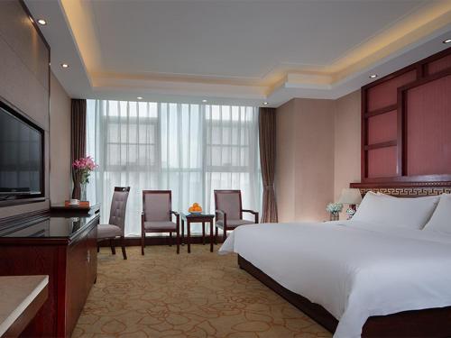 a hotel room with a bed and a table and chairs at Vienna Hotel Kunming North Caiyun Road Asia in Kunming