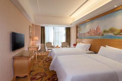 a hotel room with two beds and a flat screen tv at Vienna Hotel Shenzhen Baoneng City Plaza in Longgang