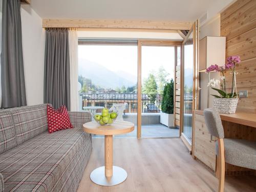 a living room with a couch and a table with a bowl of fruit at Hotel Europeo Alpine Charme & Wellness in Pinzolo