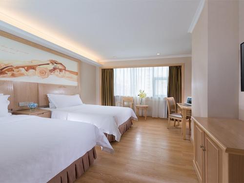 a hotel room with two beds and a desk at Vienna Hotel Shenzhen Haiwan in Shenzhen