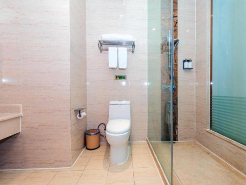 a bathroom with a toilet and a glass shower at Vienna Hotel Shenzhen Longgang Ainan Road in Longgang