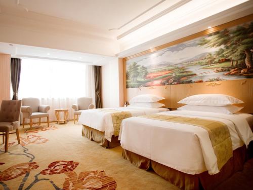 a hotel room with two beds and a painting on the wall at Vienna International Hotel Hangzhou Xintiandi Yingtai in Hangzhou