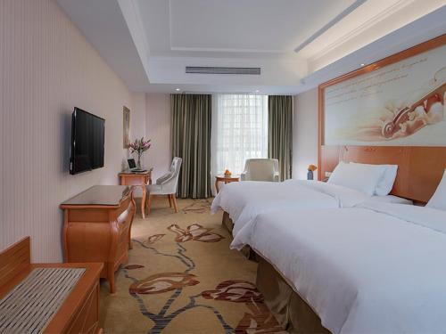 a hotel room with two beds and a television at Vienna Hotel(Zhangzhou Jiaomei WanYi square store) in Longhai