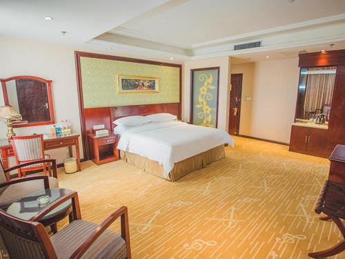 東営にあるVienna Hotel Dongying Taihangshan Roadのベッド、デスク、椅子が備わるホテルルームです。