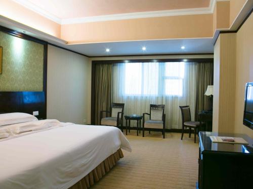 a hotel room with a bed and a table and chairs at Vienna Hotel Shenzhen Fuhua Road in Shenzhen