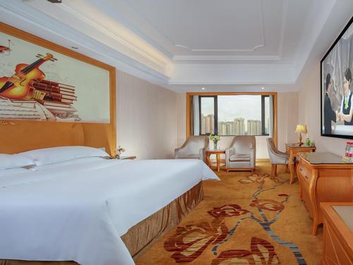 a hotel room with a large bed with a guitar on it at Vienna Hotel Chengdu Wenjiang Zhujiang Plaza in Wenjiang