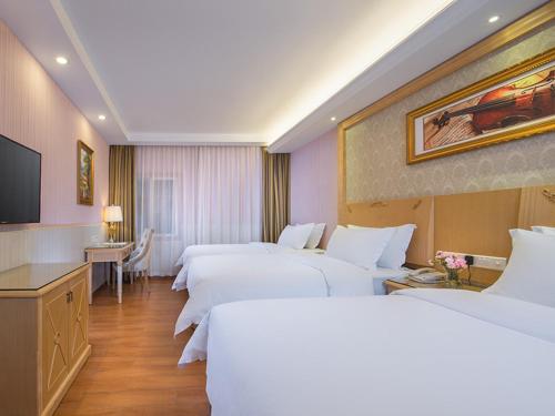a hotel room with four beds and a flat screen tv at Vienna 3 Best Hotel Exhibition Center Chigang Road in Guangzhou