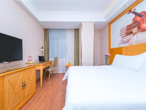 a hotel room with a bed and a desk and a television at Vienna Hotel Hubei Xiangyang Tanxi Road in Xiangyang
