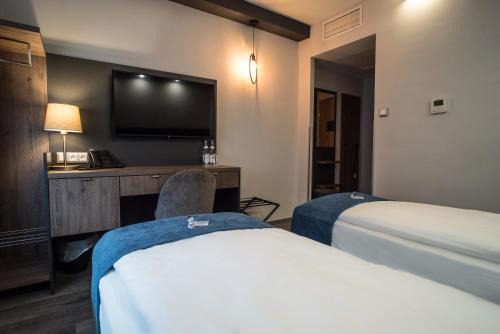 a hotel room with two beds and a flat screen tv at Hotel Palatinus in Sopron