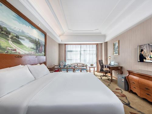 a hotel room with a large bed and a desk at Vienna International Hotel Xinyang Yangshan New District in Xinyang