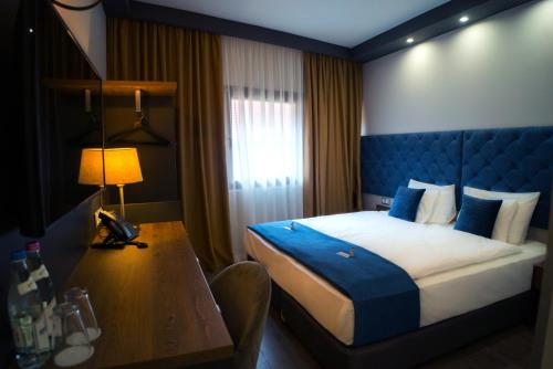 a hotel room with a bed and a desk with a lamp at Hotel Palatinus in Sopron