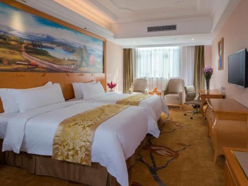 佛山市にあるVienna Hotel Foshan Ceramic Cityの大型ベッドとテレビが備わるホテルルームです。