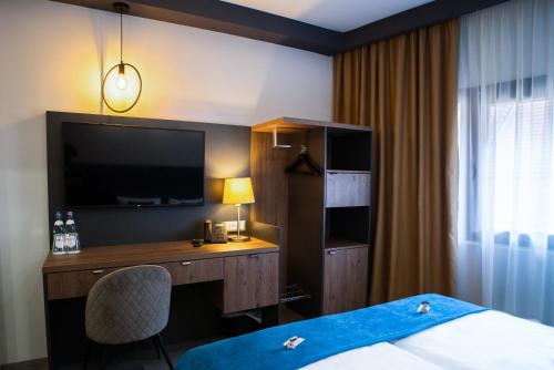 a hotel room with a bed and a desk with a television at Hotel Palatinus in Sopron