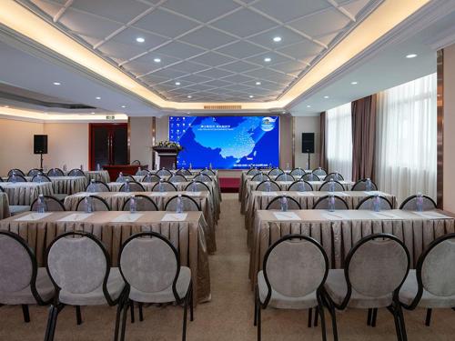 a conference room with tables and chairs and a screen at Vienna Hotel Dongguan Songshan Lake in Dongguan