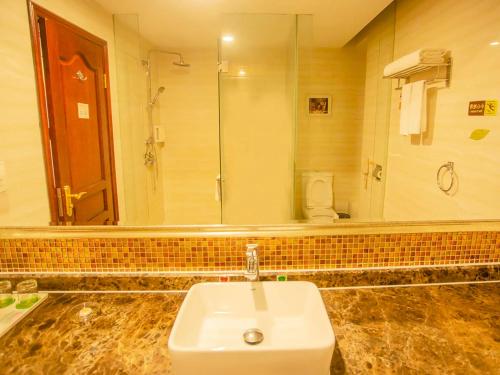 a bathroom with a sink and a large mirror at Vienna Hotel Shenzhen Songgang Liye Road in Bao'an