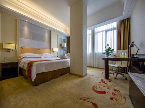 a hotel room with a large bed and a desk at Vienna Hotel Jiangmen Heshan Huamao in Heshan