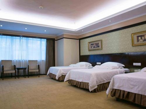 a hotel room with two beds and a table and chairs at Vienna Hotel Shenzhen Fuhua Road in Shenzhen