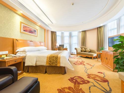 宝安にあるVienna Hotel Shenzhen View Lake Parkのベッドとテレビが備わるホテルルームです。